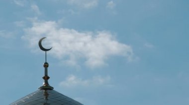 Müslüman veya İslam Din sembolü. Altın hilal Camii minare üstünde geçmiş bulutlar float. Mavi gökyüzü güneşli bir gün.