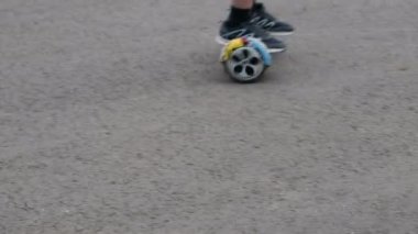 Bulanık. Genç ile bir daire içinde bir kendi kendine karşı iki tekerlekli hoverboard üzerinde gidiyor. Asfalt üzerinde hareket. Yaşam tarzı. Bacaklarım yakın çekim.