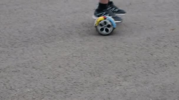 这个十几岁的年轻人骑着一圈 Hoverboard 的双轮的自我平衡 沥青上的运动 生活方式 腿是特写 — 图库视频影像