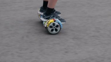 Yakın çekim, bir kendi kendine karşı sokak aktarımında iki tekerlekli ayakkabılar bacaklar mans. Hoverboard grafiti renkli asfalt hareket eder..