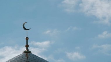 Altın hilal İslam Camii yakın çekim üstüne. Kuşlar ve minare üzerinde mavi gökyüzünde bulutlar.