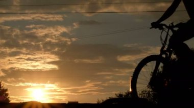 Arabalar hareket ile bir anayol tarafından geçen bir bisiklet üzerinde bir adam silüeti. Spor yaşam tarzı. Gün batımında şehir hayatı.