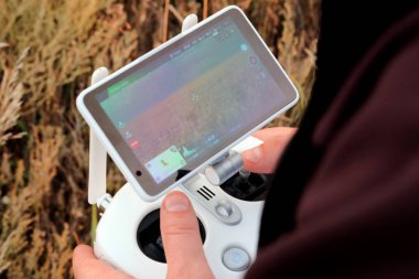 Çiftçi dronlar denetler ve bir buğday kırpma alanıyla ekranda görür. Ellerini bir adamın oyun çubuğu kontrol panelindeki bir insansız hava aracı. Gözetim, hava fotoğrafları ve video çekim kavramı.