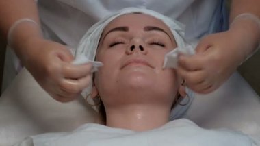 Kadın güzellik uzmanı ve güzel bir kız yaklaşımlar yüzü ile beyaz peçeteler mendiller. Güzellik Salonu yüzüne cilt temizlemek için bir ustanın elinde Close-up.