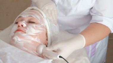 Yüz masajı özel ultrason kullanýlýyor kozmetik merkezinde. Kaldırma ve güzellik salonda kadın deri temizleme prosedürü. Bir güzellik beyaz Medikal eldiven eller