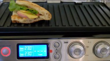 Bir elektrikli ızgara peynirli ekmek pişirme. Kız sandviç yapar. Hızlı sıcak kahvaltı.