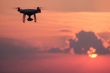Bir dron güneş ışığı bulutlar. Batan güneşin batımında ile gökyüzüne karşı quadrocopter silüeti. Havadan fotoğraf ve video. Kopya alanı.