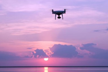 Bir dron karşı yükselen güneş ile gökyüzü göl üzerinde gündoğumu, silüeti. Quadcopter, bulutlar, sabah güneş ışığı. Uzay kopyalayın. Havadan fotoğraf ve video.