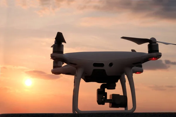 Unmanned aerial vehicle preparing to fly. Quadcopter on the background of the sunset sky.