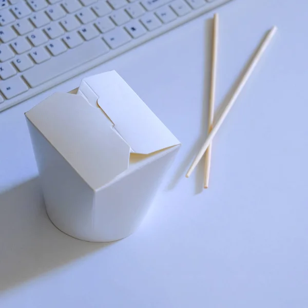 Chinese noedels staan op een witte achtergrond achter een computer. — Stockfoto
