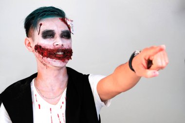 Beyaz bir arka plan üzerinde Joker suretinde bir adam portresi elini ileri gösterir. Makyaj Cadılar Bayramı tarzında. Bir tema parti ya da kostüm göstermelik cosplay. Kanlı ağız, yeşil saç. Kopya alanı.