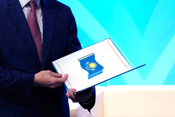 授予公务员的概念 穿着蓝色西装的男子持有哈萨克斯坦共和国国旗的开放文件夹 复制空间 — 图库照片