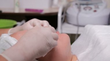 Profesyonel güzellik uzmanı krem kız Doğu türü yüzünde siliyor. Asyalı bir Müslüman kadın güzellik salonu içinde yordam gençleştirici bir yüz sırasında yalan söylüyor.