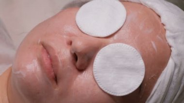 Beyaz eldivenli elleri şeffaf bir film bir Müslüman kızla çene kapsar. Yakın çekim yüz bir güzellik office içinde Güney-Doğu bir kadın. Cilt buğulaması yordamı için hazırlık.