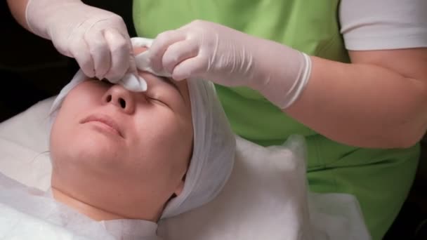 Esteticista Vestido Verde Limpa Rosto Uma Menina Oriental Com Almofadas — Vídeo de Stock