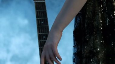 Bir akustik gitar klavyesine kadınsı bir yandan Close-up. Konser elbiseli kız gelir ve yavaşça parmaklarını dizeleri yukarı taşır. Arka planda duman. Müzik video için Tema.