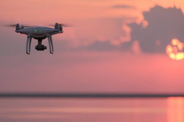 Quadrocopter günbatımında güzel bulutlar ile göl üzerinde uçar. Konsept Fotoğraf ve video ile doğa havada dron yardımıyla. Pembe bir arka plan. Kopya alanı.
