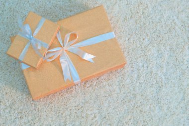 Altın renkli kurdeleler yalan beyaz yumuşak halı ile bağlı iki hediye kutuları. Tatil yeni yıl, yılbaşı, Doğum günü, Sevgililer günü ve diğerleri hazırlanma. Yukarıdan görüntüleyin. Kopya alanı.