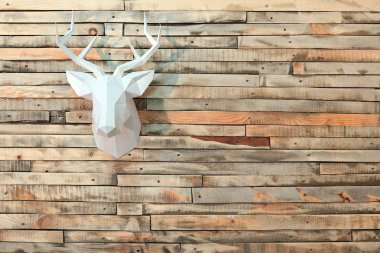 Paper moose head hanging on the wall with a view of the wooden boards. Copyspace. clipart