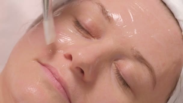 美容室の中年の女性 女性の顔をクローズ アップします 美容センターでのクライアントの肌に透明なゲルを適用するための手順 — ストック動画