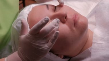 Güzellik Salonu bir Asyalı kız yüz masajı. Şevval özçelik güzellik kozmetik merkezi yordamda sırasında beyaz eldiven eller Close-up.