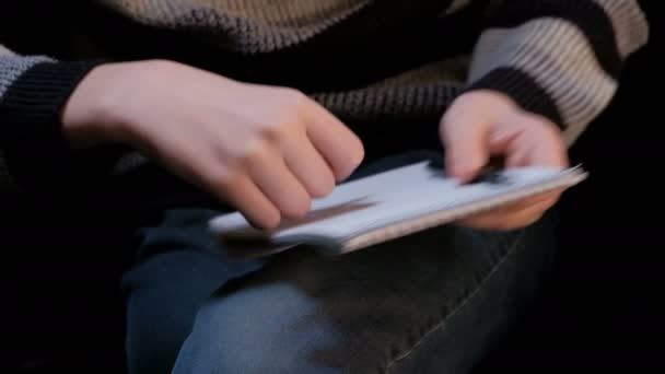彼の膝に男の手のクローズ アップ セーターとジーンズの若い男はノートと側にペンを削除し 彼の眼鏡をピックアップします 学生または作家のイメージ 試験または手紙の準備の概念 — ストック動画
