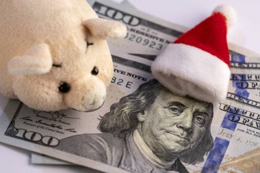 Domuz yılbaşı için harcama para. Noel Baba'nın kırmızı kap üzerinde yatıyor yüz dolarlık banknot, Birleşik Devletler Başkanı portresi. Toplantı Noel ve finans.