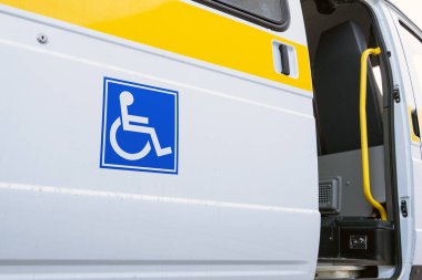 Beyaz veri yolu ile engelliler için mavi bir işaret. Engelliler için özel bir araç açık kapı. Sarı çubuğu ve küpeşte.