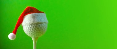 Kırmızı bir Santa Claus şapka bir sahada monte bir golf topu üzerinde yıpranmış. Konuyla ilgili kopya alanı Golf Noel ve yeni yıl ile uzun bir başlık. Yeşil arka plan doymuş.