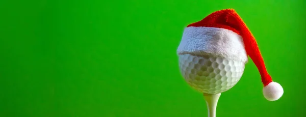 Noel ve yeni yıl kutlamak bir golfçü için bir kartpostal için boş bırakın. Sahada monte golf topu Noel Hediyelik eşya şapka giyiyor. Uzay kopyalayın. Parlak yeşil renkli.