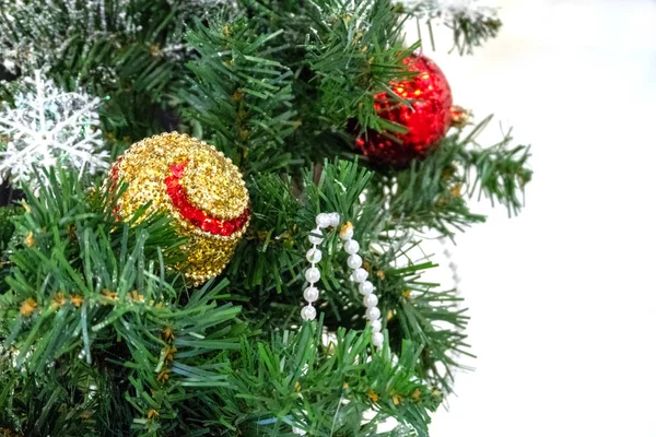 Parte de un árbol de Navidad verde con bolas brillantes sobre un fondo blanco. Decoración de Navidad, juguetes, copos de nieve y perlas. Diseño de la habitación para las vacaciones de invierno . —  Fotos de Stock