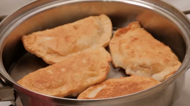 Beautiful fried meat pies are cooked in a pan in hot vegetable oil. Close-up. Metal shiny dishes. — Stock Video