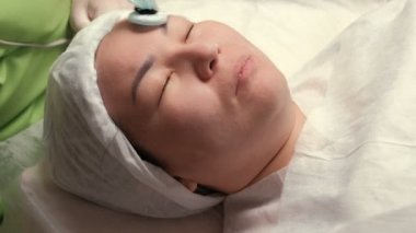 Temizlik ve cilt gençleştirme için modern kozmetik prosedür. Darsonvalization. Donanım kozmetik. Bir kız Asya görünüm güzellik salonu.