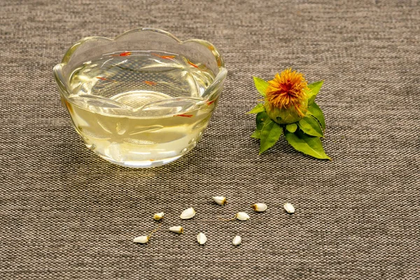 Carthamus tinctorius, Amerikan safran, vahşi thistle. Yağı, çiçek ve Aspir tohumları bir bez arka planda gri çuval bezi severim. Yakın çekim. Eski zamanlardan beri yağlı tohum ve boyama, kültür olarak bilinen.