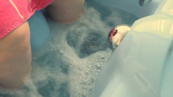 Die Beine einer älteren Frau in einem Bad mit Wasser. Nahaufnahme. Hydromassage der unteren Extremitäten. medizinisches Therapieverfahren. — Stockvideo