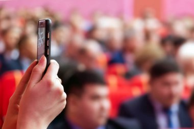 Bulanık. Canlı yayın blogger veya bir cep telefonu kullanarak toplantı salonunda gazeteci. Pembe bir arka plan. Dikey fotoğraf veya video modunda. Yumuşak odak. Kopya alanı.