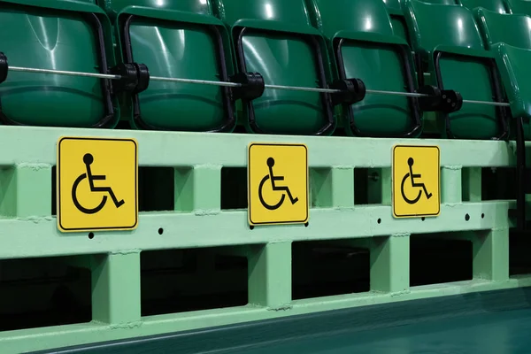 Places for disabled in the auditorium. Green seats in a stadium or in a sports complex. concept of protecting the rights of people with a violation of the musculoskeletal system. Yellow symbol.