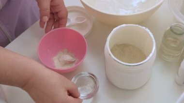 Profesyonel bir Kozmetolog bir güzellik salonunda gençleştirici bir prosedür için besleyici bir yosun maskesi hazırlar. Pembe kozmetoloji kupasında malzemeyi karıştırma.