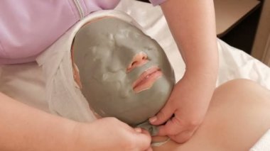 Bir güzellik salonunda orta yaşlı Asyalı bir kadının yüzüne aljinat maskesi çıkarma. Güzellik yavaşça gözyaşları ve kız cilt gelen kauçuktan kitle kaldırır. Renk düzeltmesi olmadan RAW video