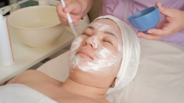 Schoonheidsspecialiste Geldt Een Massage Crème Het Gezicht Van Een Aziatische — Stockvideo