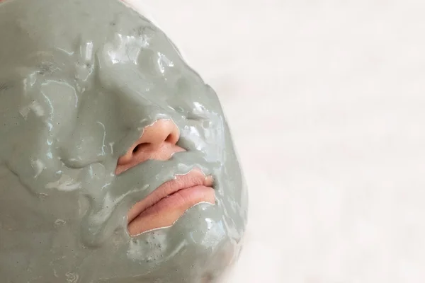 Close-up. A woman's face is covered with an alginate mask. Cosmetic procedure. Gray frozen mass on the head of a woman. In isolation. Copy space. — Stock Photo, Image