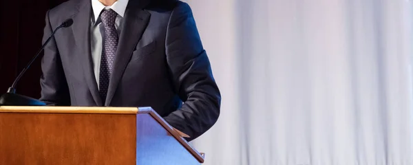 Discurso de un hombre abstracto en un traje en el escenario en el stand para actuaciones. Tribuna o cátedra para el orador oficial, presidente o profesor. Primer plano. Copiar espacio . — Foto de Stock