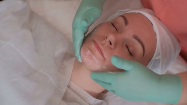 Kosmetolog i gröna handskar soaping ansiktet på en vacker flicka. Kosmetisk förfarande för rengöring av kvinnlig hud i en skönhetssalong. Närbild. — Stockvideo