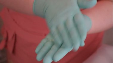 Yeşil eldiven ve pembe halategotovit toz ve güzel bir Avrupalı kız yüzüne uygulanan temizleyici. Bir güzellik salonunda kadın cilt temizliği için kozmetik prosedür. Sağlık, moda
