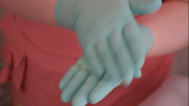 Αισθητικός σε πράσινα γάντια και ροζ halategotovit αφρό από τη σκόνη και εφαρμόζεται στο πρόσωπο ενός όμορφου Ευρωπαϊκού κοριτσιού. Αισθητική διαδικασία για τον καθαρισμό της γυναικείας επιδερμίδας σε ένα σαλόνι ομορφιάς. Υγεία, μόδα — Αρχείο Βίντεο