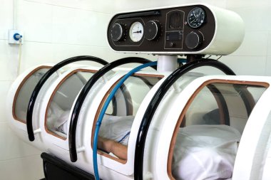 Pressure chamber. The man lies in a white altitude chamber. Equipment in a hospital or intensive care center for seriously ill people or astronauts after an overload. Close up. clipart