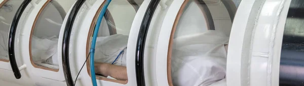 Een hyperbare kamer met een man liggen binnen. Behandeling in een zuurstof-capsule. Een druk kamer concept. Apparatuur in het ziekenhuis voor ernstig zieke personen of een laboratorium voor astronauten en piloten. — Stockfoto