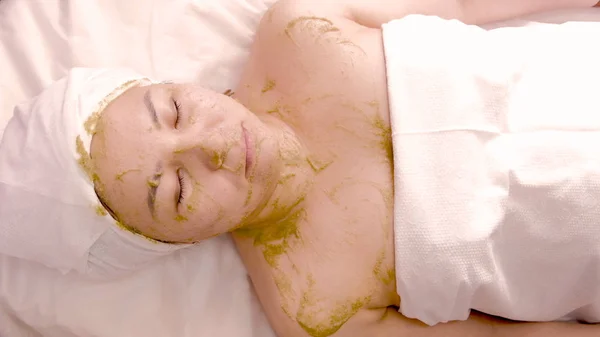 Relaxed asian woman resting in spa. Green cosmetic mask based on green algae. Cosmetology. Body and face care. Spa treatments. — Stock Photo, Image