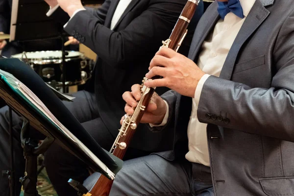 Egy férfi öltöny játszik a klarinét. Fúvószenekar. Zenei témát. Férfi ujjaival nyomja meg a gombokat a cső. Közeli kép:. — Stock Fotó