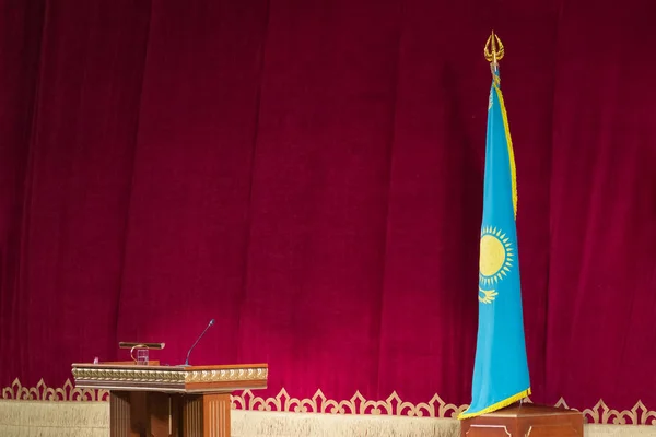 Concepto Kazajstán noticias oficiales. Bandera de la República de Kazajstán y mesita de noche para el orador sobre fondo rojo. Sin gente. Copiar espacio . —  Fotos de Stock
